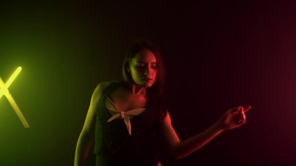 Menina morena bonita em uma roupa nua dançando em um estúdio com luz multicolorida, fundo, câmera lenta — Vídeo de Stock
