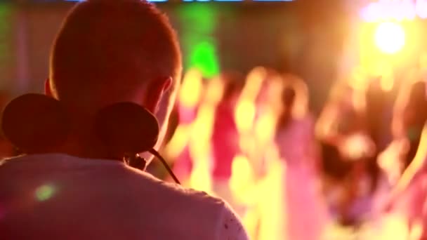 DJ maschio in cuffia ballare in un nightclub contro una folla di persone, spazio copia, slow mo — Video Stock