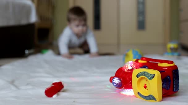 Malý krásný chlapeček si hraje s hračkami doma. 8 měsíců starý chlapec, běloch. Velké hnědé oči — Stock video