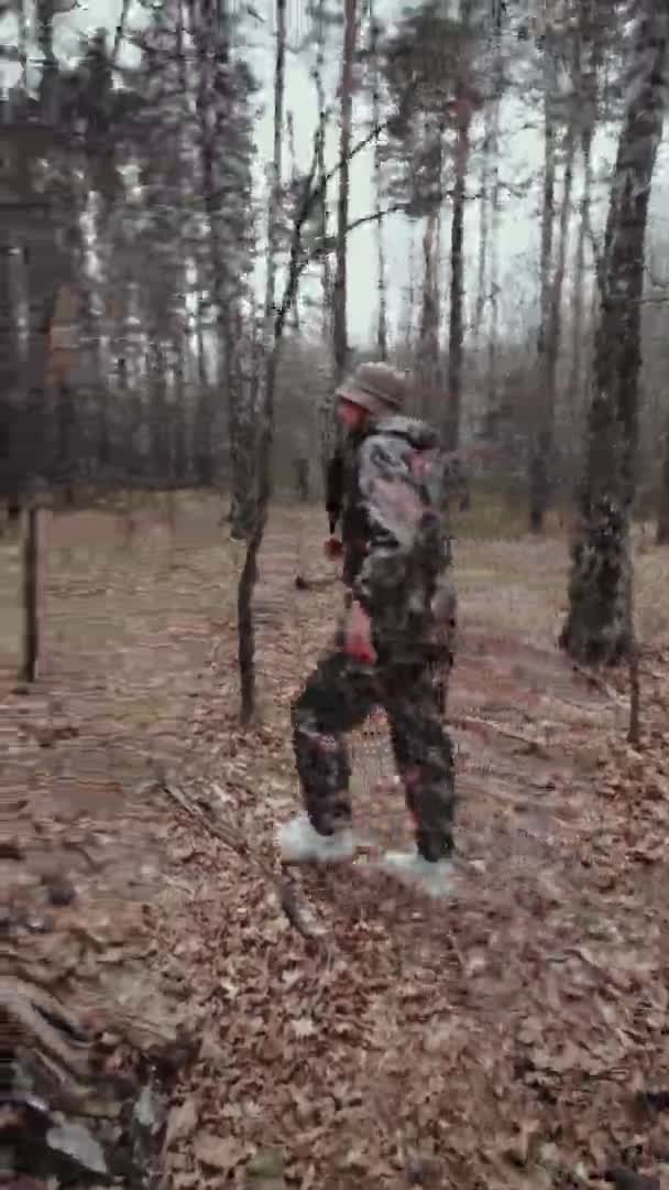 Hunter guardabosques vestido con traje de camuflaje le dice algo a la cámara. Disparo vertical. Extraño corresponsal con micrófono. Hombre blogger caucásico con bigote y rastrojo en sombrero de panama — Vídeo de stock