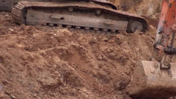 Sürüngen kazıcı bir inşaat sahasında kovayla toprağı kazıyor, yakın plan, endüstri. — Stok video