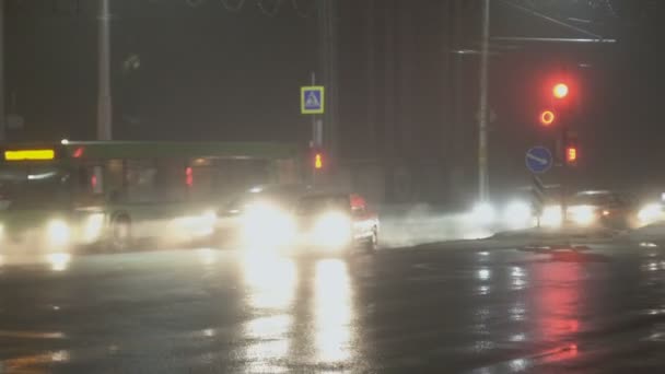 車、車、自動信号機で横断道路を通過します。冬の霧の中で夜の街。湿式アスファルトの反射。ヘッドライトからの光。霧や霞、道路交通のための視界不良、悪天候 — ストック動画