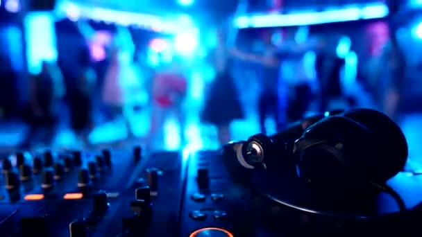 DJ musik kontrolpanel med hovedtelefoner på baggrund af dansende mennesker i en natklub, kopiere plads – Stock-video