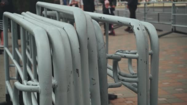 De nombreuses clôtures métalliques mobiles portables des gens sont empilées et se tiennent à côté de la route lors d'un événement de masse en ville. Barrières de sécurité policière. Construction de barricades de sécurité . — Video