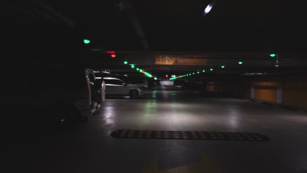 Dentro de aparcamiento subterráneo público más oscuro moderno en el sótano del centro comercial y centro comercial de entretenimiento. Los coches están estacionados en el estacionamiento. Gran garaje grande — Vídeo de stock