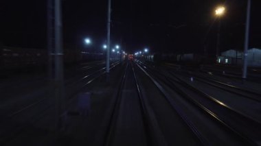Demiryolu treni gece demiryolu çatalından geçer. Hareket halindeki son vagonun arka penceresinden raylara bakın. Seyahat ve turizm konsepti. Yolcu treni şehir dışına çıkıyor.
