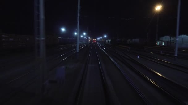 Železniční vlak projíždí v noci železničním rozcestím. Pohled na kolejnice ze zadního okna posledního vozu v pohybu. Koncept cestování a cestovního ruchu. Osobní vlak jedoucí mimo město — Stock video