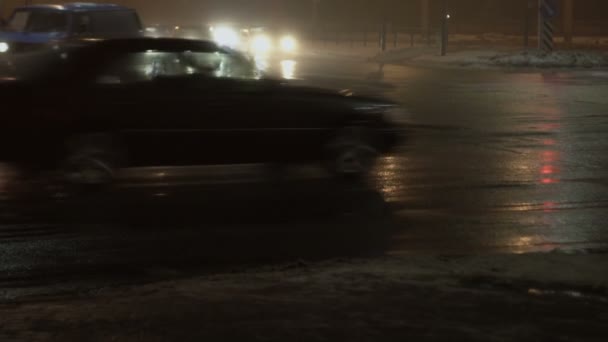 Autos, Fahrzeuge passieren die Kreuzung in der Nacht. Stadt im Nebel. Zeitlupe. Reflexion auf nassem Asphalt. Licht von Stirnlampen. Schlechte Sicht für den Straßenverkehr, schlechtes Wetter — Stockvideo