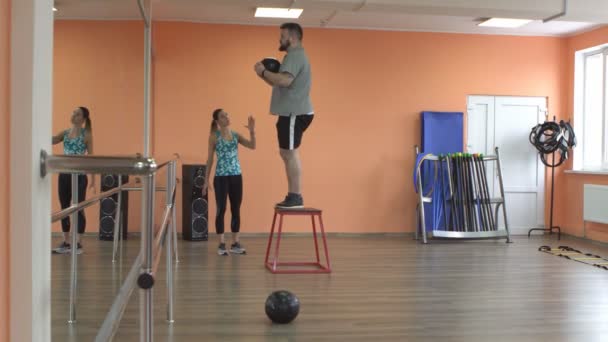 Joven chica caucásica entrenador entrena a un hombre con barba en un gimnasio de fitness para quemar grasa. Problemas de sobrepeso, salud — Vídeo de stock