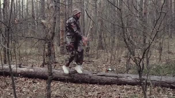 Idegen férfi vadász álruhába öltözve táncos techno. Egy 30 éves erdőőr hülyéskedik. Fehér blogger bajusszal és borostával panama kalapban és tornacipőben ugrik és rázza a testét. — Stock videók