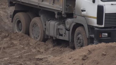 Bir inşaat kamyonu kumda durdu. Merkez diferansiyel kilit, arka plan, endüstri. Tekerlek tutuşu