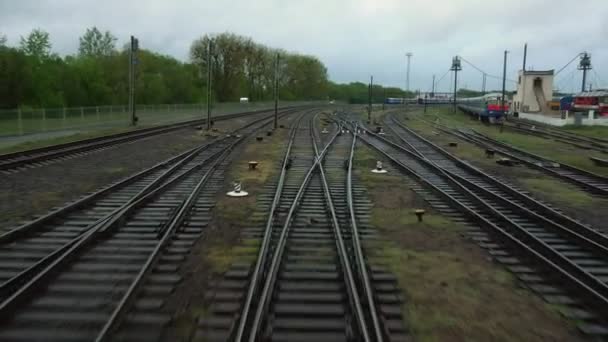 O trem ferroviário passa através do garfo ferroviário. Vista em trilhos da janela traseira da última carruagem de ônibus durante o dia em movimento. Viagens e turismo conceito. Comboio de passageiros que sai da cidade — Vídeo de Stock