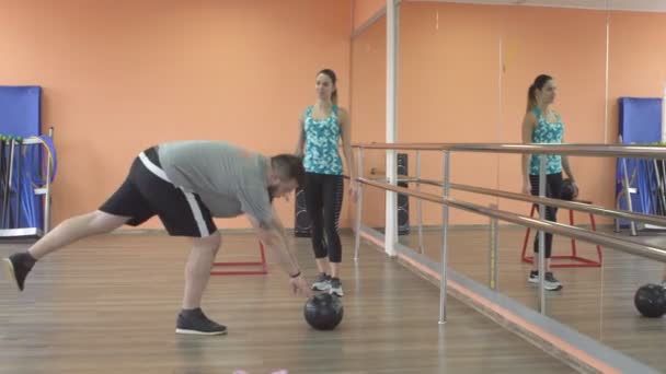 Jovem treinadora caucasiana treina um homem com barba em um ginásio de fitness para queimar gordura. Problemas de excesso de peso, Saúde — Vídeo de Stock