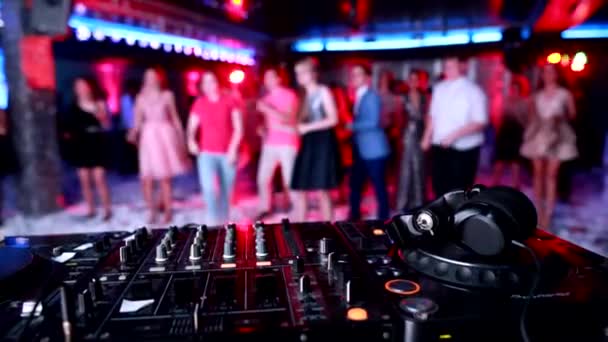 Panel de control de música DJ con auriculares en el fondo de la gente bailando en una discoteca, espacio para copiar — Vídeos de Stock