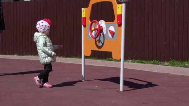 Mała piękna dziewczynka bawi się na nowoczesnym placu zabaw ze swoją mamą. Słoneczna wiosenna pogoda, nowy plac zabaw ze zjeżdżalniami i huśtawkami, szczęśliwy — Wideo stockowe