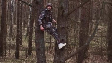 Kamuflaj kıyafeti giymiş avcı orman bekçisi ağaçta oturuyor. LSD narkotik etkisi, psikolojik bozukluk konsepti. Garip adamın kafası karışmış. Panama şapkalı çılgın, beyaz bir adam. Umutsuzluk