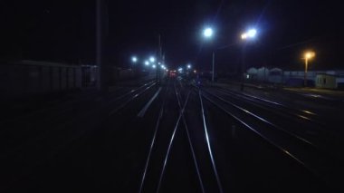 Demiryolu treni demiryolu çatalından geçer. Son vagon vagonunun arka penceresinden gece hareket halindeki raylara bakın. Seyahat ve turizm konsepti. Yolcu treni şehir dışına çıkıyor.