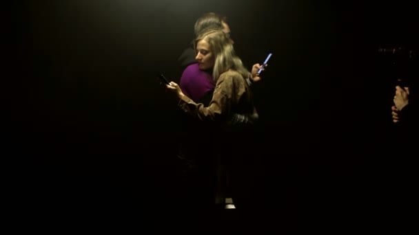 在片场，操作员用一对深爱着黑色背景智能手机的情侣拍摄了一段视频 — 图库视频影像