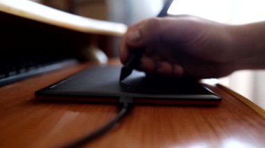 Bir adam grafiksel tablet kullanarak bilgisayarın başında çalışır ve çizer.