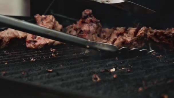 Kucharz przygotowuje świeże mięso na grillu, odwraca mięso do jednolitego smażenia. Soczysty apetyt Mięso jest grill, slow mo, grillowane mięso — Wideo stockowe