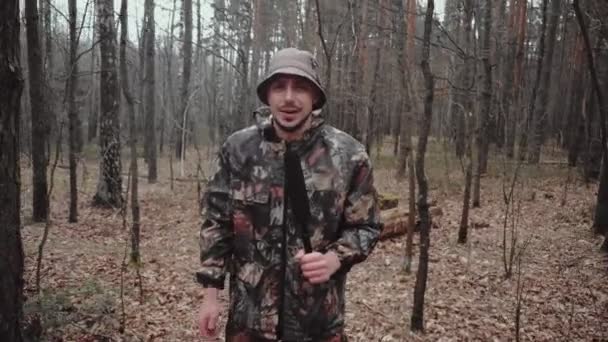 Hunter garde forestier vêtu d'un costume de camouflage raconte quelque chose à la caméra. Étrange correspondant reporter avec microphone. 30 ans caucasien homme blogueur avec moustache et chaume dans panama chapeau — Video