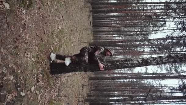Κυνηγός δασοφύλακας ντυμένος με στολή καμουφλάζ σκαρφαλώνει στο δέντρο. Κάθετη βολή. Ο παράξενος άνθρωπος είναι μπερδεμένος. LSD ναρκωτικό αποτέλεσμα, ψυχολογική διαταραχή έννοια. Ψυχεδελικό πρόσωπο — Αρχείο Βίντεο