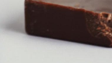 Makro shot, badem fıstıklı, ısırılmış sütlü çikolata paketlenmeden beyaz arka planda. Diyet ve sağlıksız gıda konsepti. Tatlı ve lezzetli bir tatlı. İzole edilmiş. Kalori ve şeker.