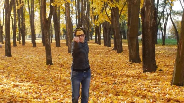 Blanke man stak zijn hand naar voren bootst Superman en gaat vooruit door de herfst park, slow motion — Stockvideo