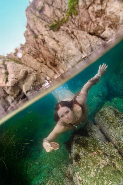 Девушка с раковиной под водой — стоковое фото