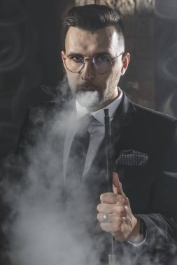 Modaya uygun bir adam sigara içiyor.