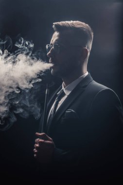 Modaya uygun bir adam sigara içiyor.