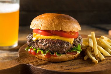 Ev yapımı Grass Fed Cheeseburger, yanında patates kızartması ve bira.