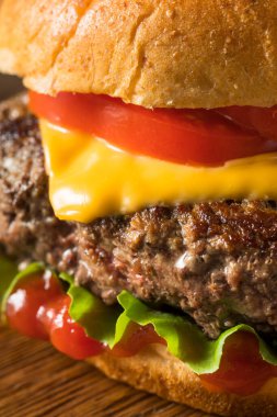 Ev yapımı Grass Fed Cheeseburger, yanında patates kızartması ve bira.