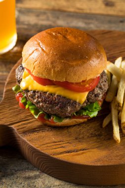 Ev yapımı Grass Fed Cheeseburger, yanında patates kızartması ve bira.