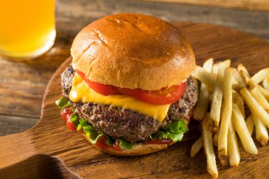 Ev yapımı Grass Fed Cheeseburger, yanında patates kızartması ve bira.