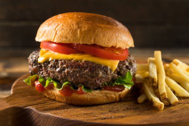 Ev yapımı Grass Fed Cheeseburger, yanında patates kızartması ve bira.