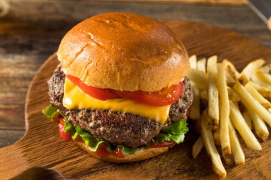 Ev yapımı Grass Fed Cheeseburger, yanında patates kızartması ve bira.