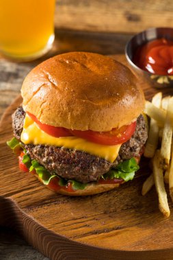 Ev yapımı Grass Fed Cheeseburger, yanında patates kızartması ve bira.