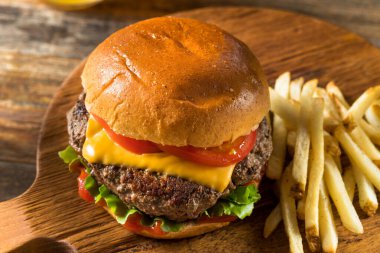 Ev yapımı Grass Fed Cheeseburger, yanında patates kızartması ve bira.
