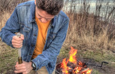 Genç bir adam cebinde bıçak kamp sırasında kullanarak şarap bir şişe açar