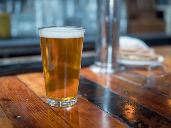 Full pint glas öl sitter på bardisk — Stockfoto