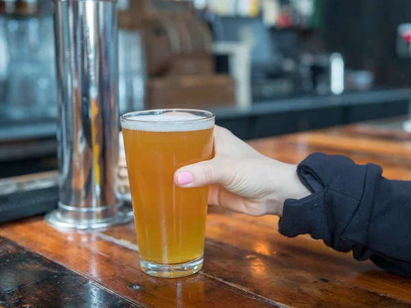 Kvinna att nå för pint glas Ipa i en bar i ett bryggeri — Stockfoto