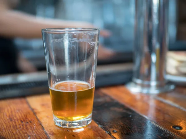 Nästan tömma pint glas öl sitter på bar för senaste samtal — Stockfoto