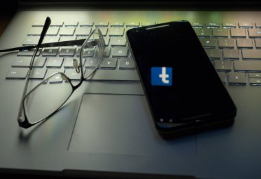 Ekranda yansıtan Facebook logolu dizüstü bilgisayarda oturup telefon
