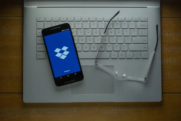 Carga de aplicaciones de Dropbox en un teléfono Android en una habitación oscura — Foto de Stock