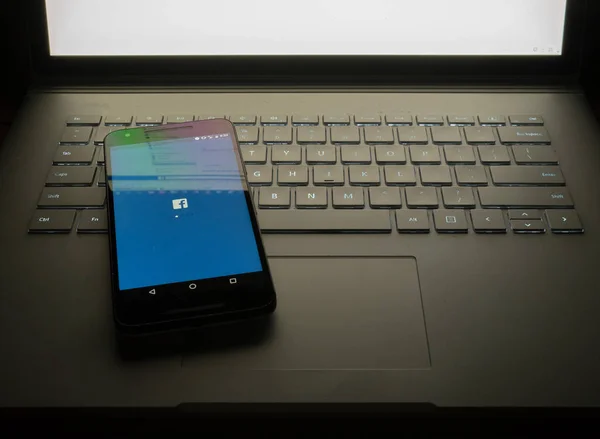 Facebook masaüstü site sc üzerinde oturan ile dizüstü bilgisayarda oturup telefon