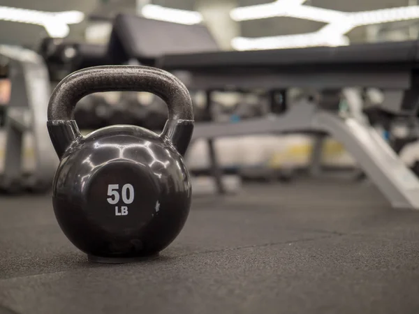 Kettlebell de 50 libras con un banco borroso y un conjunto de peso en el fondo — Foto de Stock