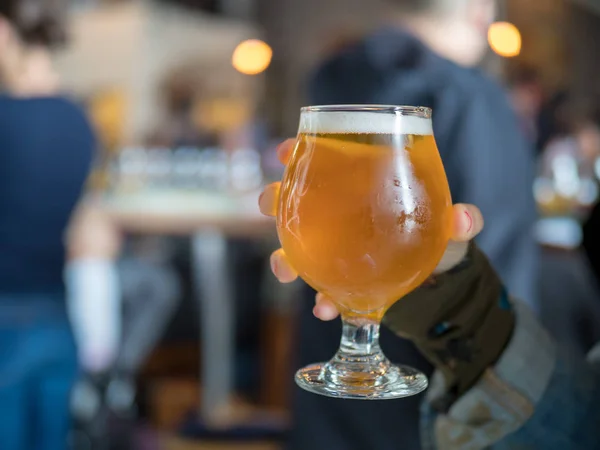 Handen håller en lättöl liten drink i bar/bryggeri — Stockfoto