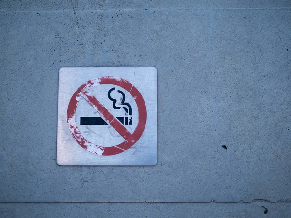 Señal de no fumar desgastada colocada en una pared — Foto de Stock