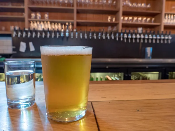 Склянка пива на барній стійці зверху, поруч з водяним склом — стокове фото